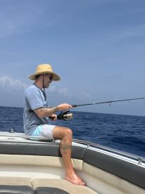 Angler casting a line while fishing on a boat in open water, showcasing a relaxed day on the ocean.
