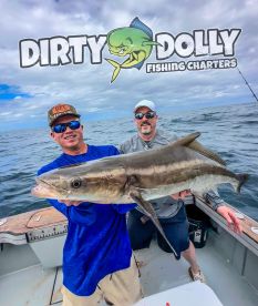 Two anglers proudly displaying a large Cobia while fishing aboard a charter boat, showcasing the excitement of a successful offshore fishing trip.