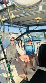 Three friends relaxing inside the cabin of a fishing boat, enjoying a sunny day at the marina.