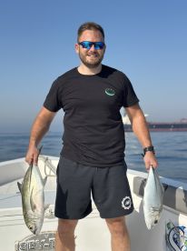 Angler proudly displaying two large fish aboard a fishing boat, showcasing a successful day on the water.