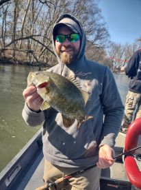 An angler proudly displaying a large Smallmouth Bass while fishing on a river, showcasing the thrill of freshwater fishing.